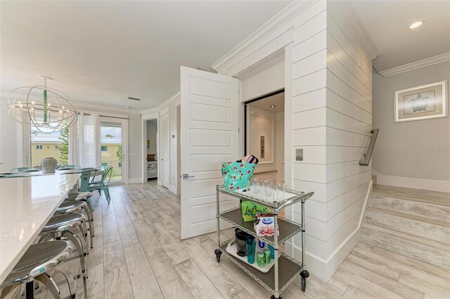 corridor with ornamental molding, light hardwood / wood-style floors, and a notable chandelier