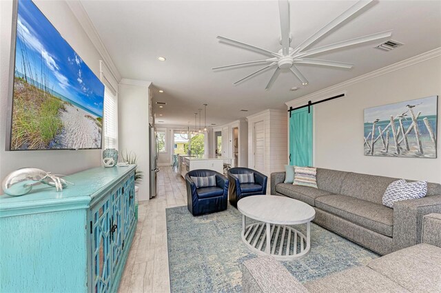 living room featuring hardwood / wood-style floors, ceiling fan, crown molding, and a barn door