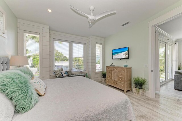 bedroom featuring ceiling fan, light hardwood / wood-style floors, access to exterior, and multiple windows