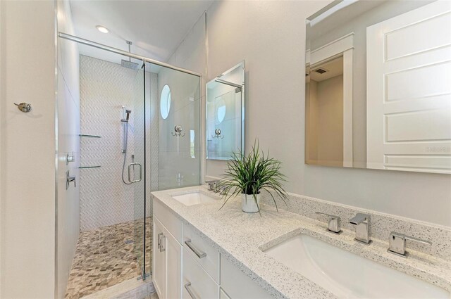 bathroom featuring an enclosed shower and dual vanity