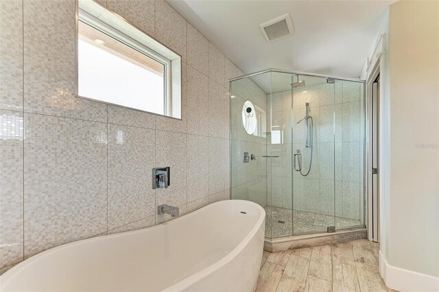 bathroom with hardwood / wood-style floors, tile walls, and shower with separate bathtub