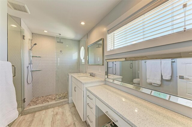 bathroom with an enclosed shower, toilet, wood-type flooring, and large vanity