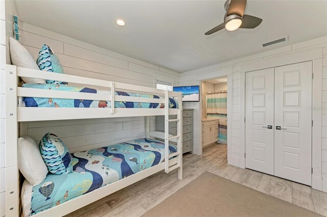 bedroom featuring a closet, light hardwood / wood-style flooring, ceiling fan, and connected bathroom