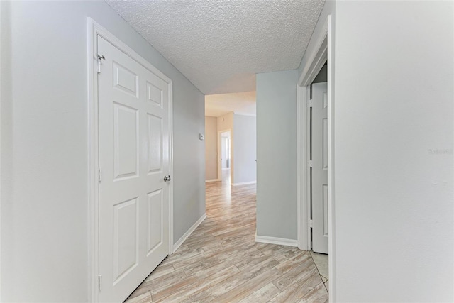 hall featuring light hardwood / wood-style flooring and a textured ceiling