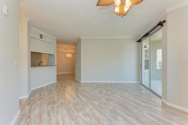 empty room featuring a barn door, crown molding, ceiling fan with notable chandelier, a textured ceiling, and light wood-type flooring