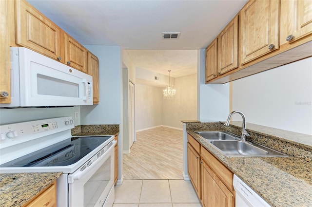 kitchen with sink, white appliances, light tile flooring, decorative light fixtures, and an inviting chandelier