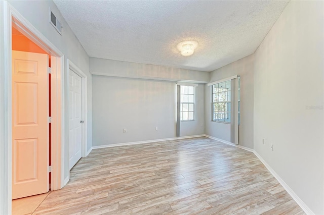 spare room with light hardwood / wood-style floors and a textured ceiling