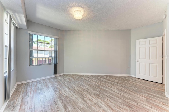 unfurnished room featuring light wood-type flooring and a textured ceiling