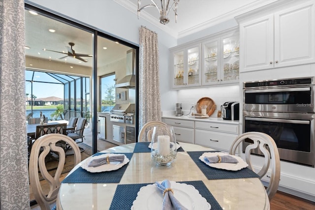 dining room featuring a water view, crown molding, ceiling fan, and dark wood-type flooring