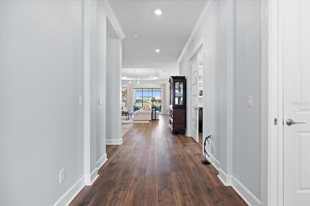 hall with a chandelier, dark hardwood / wood-style floors, and ornamental molding