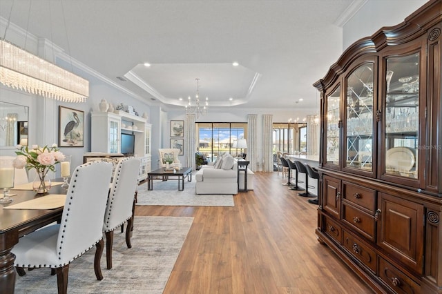 dining space featuring a chandelier, hardwood / wood-style floors, a raised ceiling, and ornamental molding