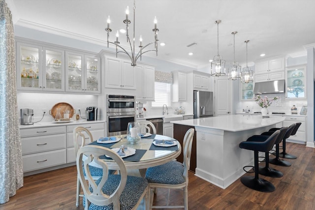 kitchen with white cabinets, appliances with stainless steel finishes, dark hardwood / wood-style floors, and a kitchen island