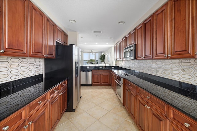 kitchen featuring dark stone countertops, stainless steel appliances, backsplash, and light tile floors