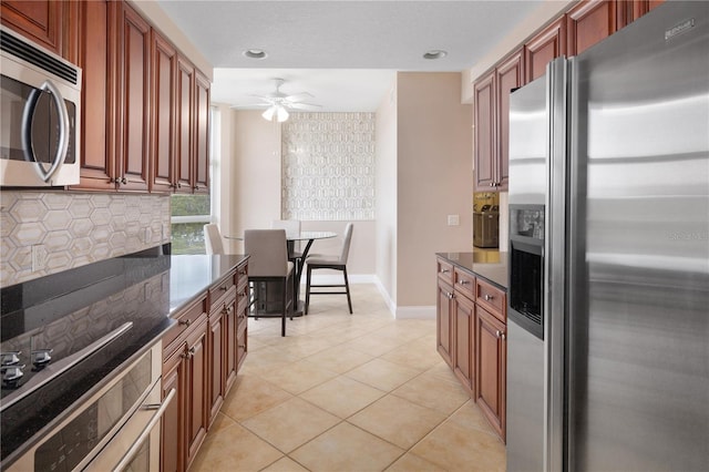 kitchen with ceiling fan, stainless steel appliances, tasteful backsplash, dark stone countertops, and light tile floors