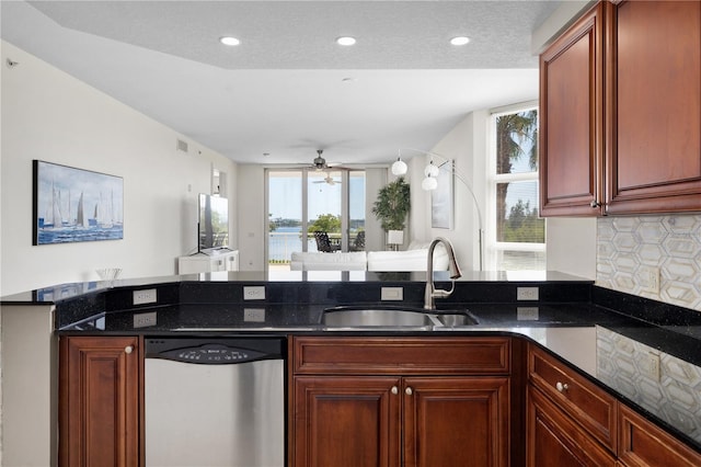 kitchen featuring ceiling fan, sink, dishwasher, dark stone counters, and kitchen peninsula