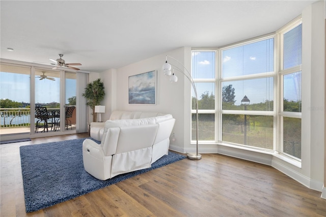 living room featuring wood-type flooring, ceiling fan, a healthy amount of sunlight, and expansive windows