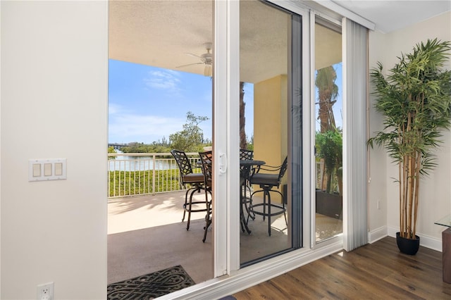 entryway with a water view, ceiling fan, dark hardwood / wood-style flooring, and a textured ceiling