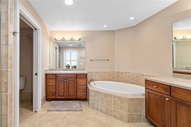 bathroom featuring tiled bath, vanity, toilet, and tile flooring