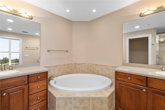 bathroom featuring a relaxing tiled bath and vanity