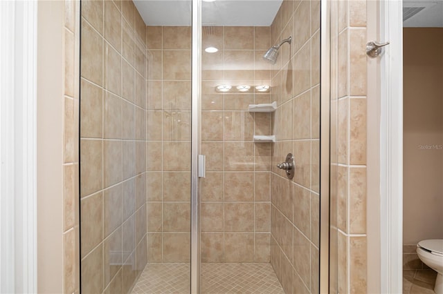 bathroom featuring a shower with door and toilet