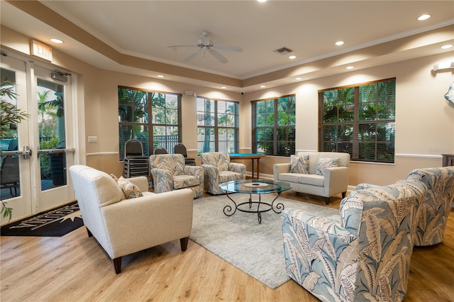 living room with ornamental molding, french doors, ceiling fan, and light wood-type flooring