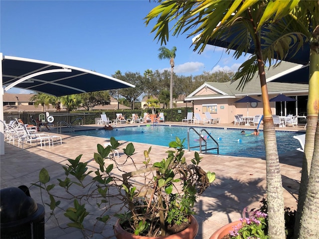 community pool with a patio area and fence