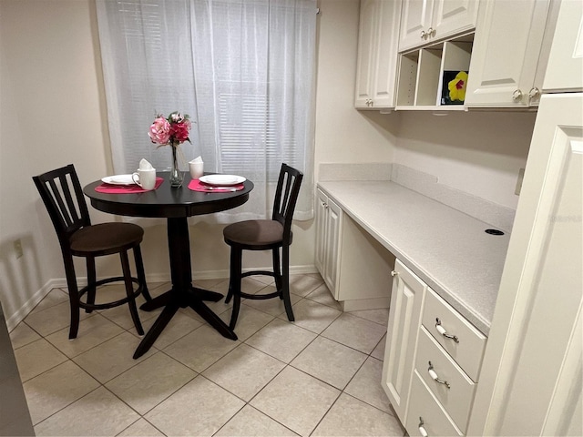 dining room featuring built in study area, baseboards, and light tile patterned floors