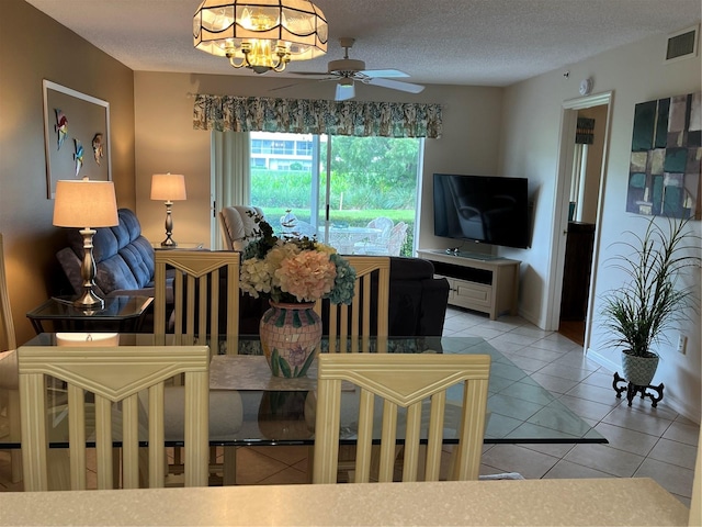 dining room featuring light tile patterned floors, baseboards, visible vents, a textured ceiling, and ceiling fan with notable chandelier