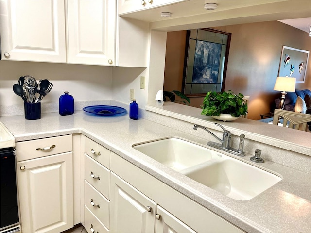 kitchen with white cabinets, light countertops, and a sink