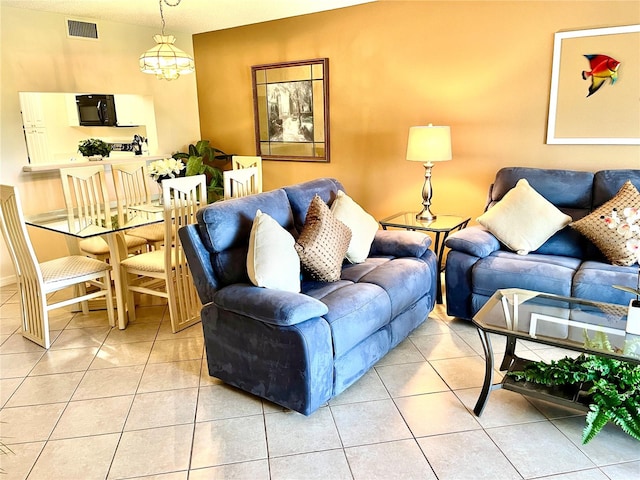 living area with light tile patterned flooring, visible vents, and an inviting chandelier