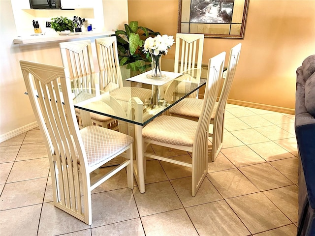 tiled dining space featuring baseboards