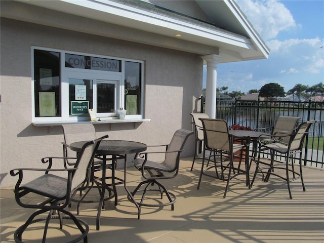 view of patio featuring a water view and fence