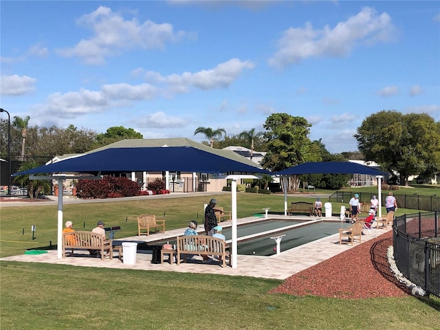 view of community featuring a lawn and fence