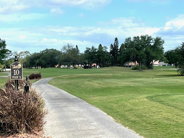 surrounding community featuring golf course view and a yard