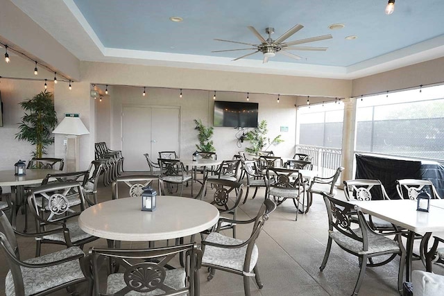 dining space with a raised ceiling and a ceiling fan