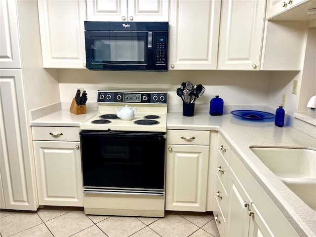 kitchen featuring white cabinets, black microwave, light countertops, and electric stove