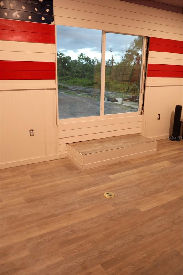 unfurnished room with wood-type flooring and wooden walls