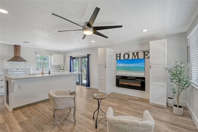 living room with light wood-type flooring, a textured ceiling, and ceiling fan