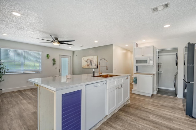 kitchen with an island with sink, white cabinets, white appliances, ceiling fan, and sink