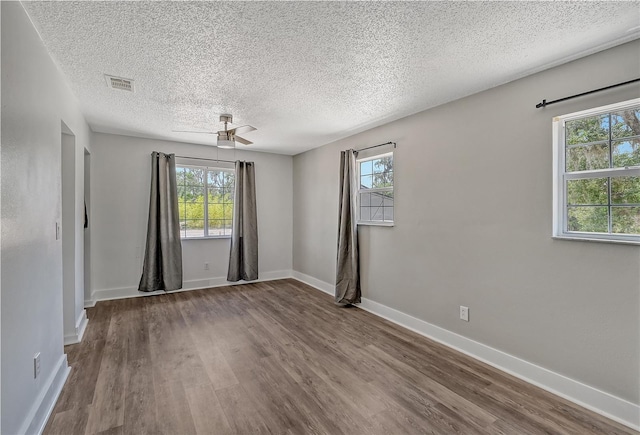 empty room featuring ceiling fan, hardwood / wood-style flooring, plenty of natural light, and a textured ceiling