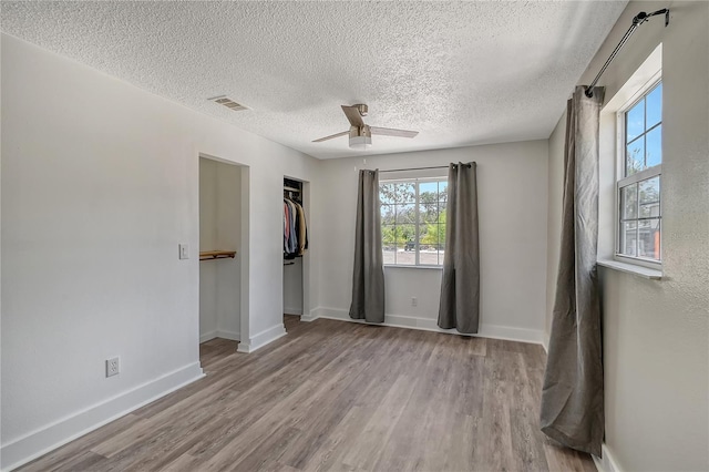 empty room with light wood-type flooring, a textured ceiling, and ceiling fan