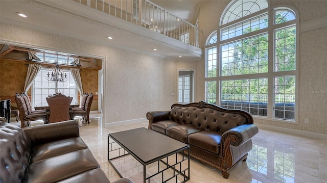 tiled living room with plenty of natural light, a towering ceiling, a chandelier, and ornamental molding