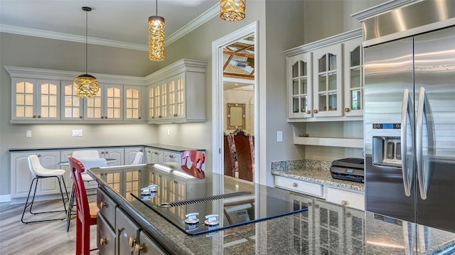 kitchen featuring black electric stovetop, high end fridge, ornamental molding, dark stone counters, and light hardwood / wood-style floors