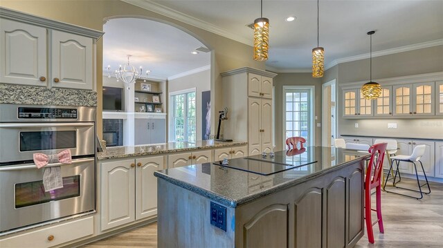 kitchen featuring a center island, double oven, decorative light fixtures, and light wood-type flooring