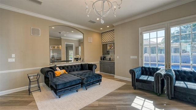 living room featuring ornamental molding, sink, light hardwood / wood-style flooring, and a chandelier