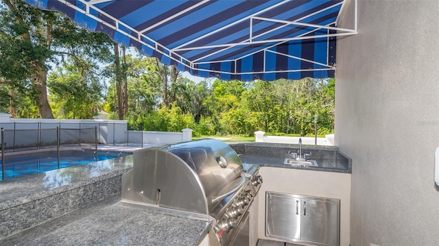 view of terrace featuring a fenced in pool, sink, and grilling area