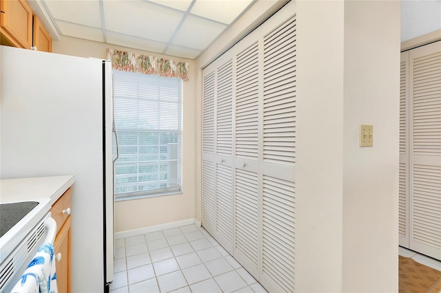 kitchen with white refrigerator, light tile floors, and range