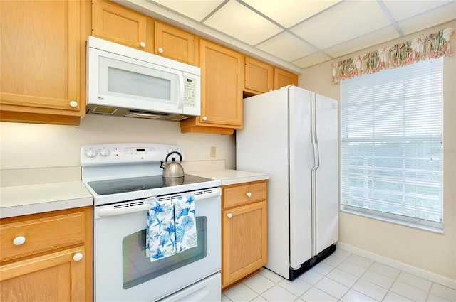 kitchen with a drop ceiling, white appliances, light tile flooring, and plenty of natural light