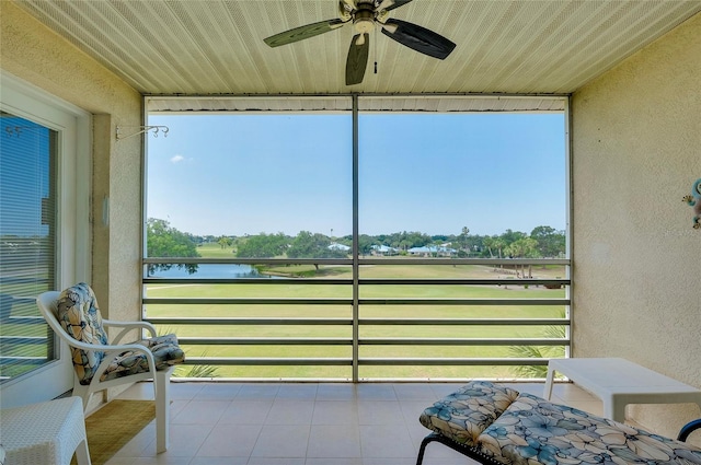 sunroom with ceiling fan and a water view