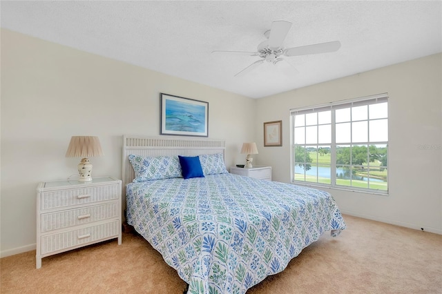 bedroom with light colored carpet, a textured ceiling, a water view, and ceiling fan